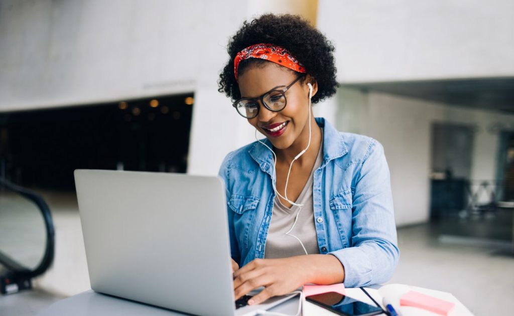 Woman playing on laptop with earphones
