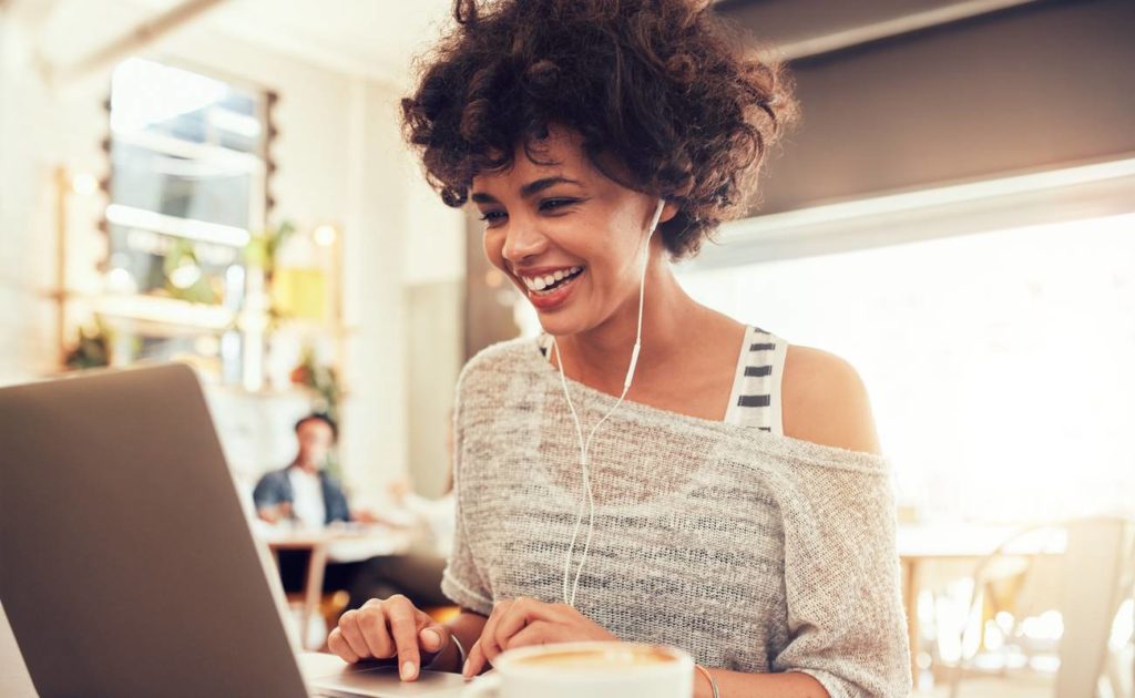 Smiling woman sitting in a coffee shop working on laptop