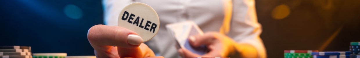 Casino dealer lifting dealer button surrounded by chips.