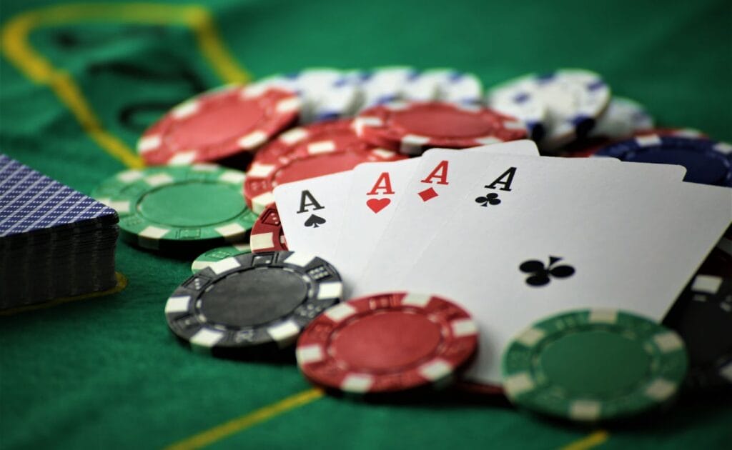 Poker ace cards and colorful casino chips on a poker table.