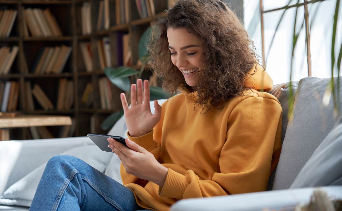 Woman sitting on sofa on smartphone video call