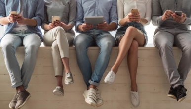 People in casual clothes using smart devices while sitting in a row.