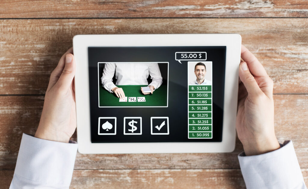 A closeup of a dealer dealing cards on a tablet that is being held.
