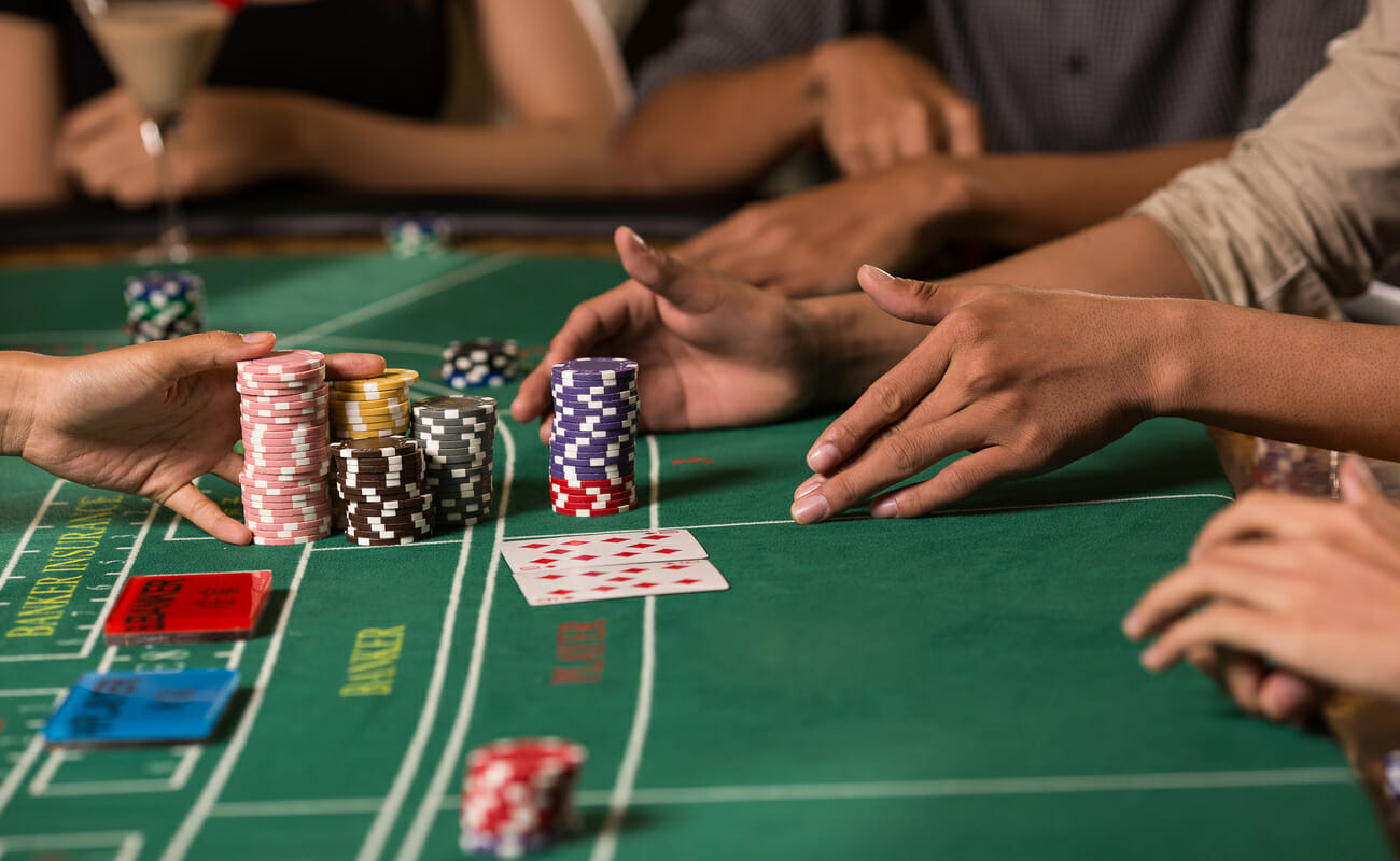 A winner at a baccarat table collecting their chips.