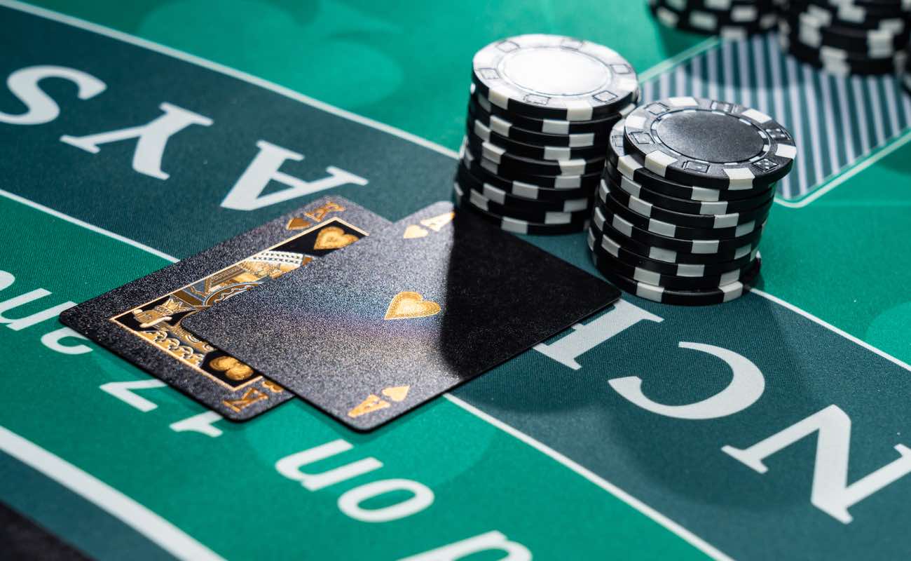 Closeup of a blackjack table at a casino with two black playing cards and two stacks of black chips