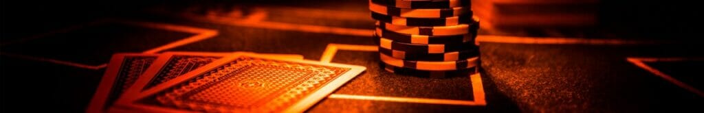 Cards and chips on a poker table in a red light.