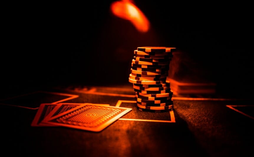 Cards and chips on a poker table in a red light.