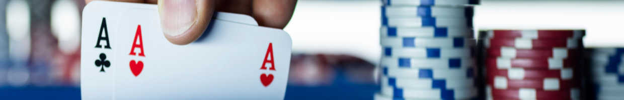 A person holds up two aces next to a stack of chips