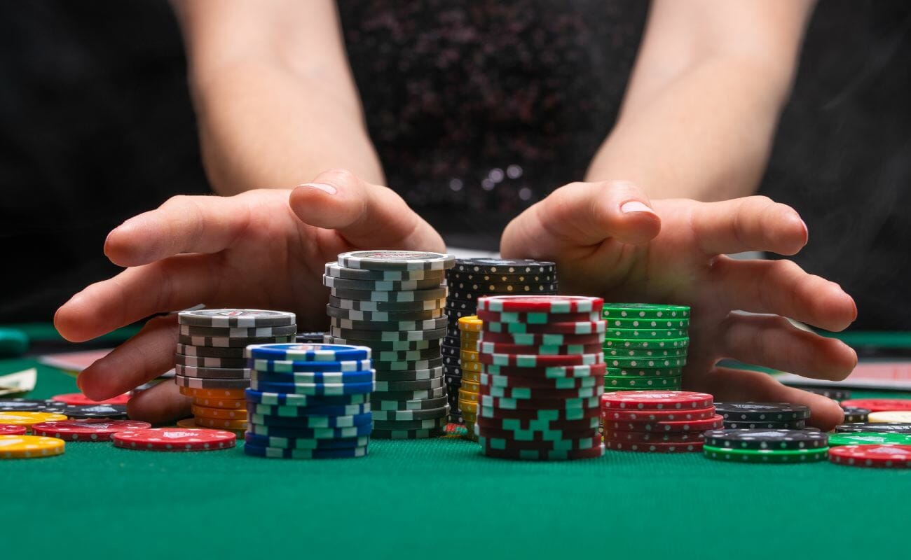 Poker chips and fingers on a green felt table.