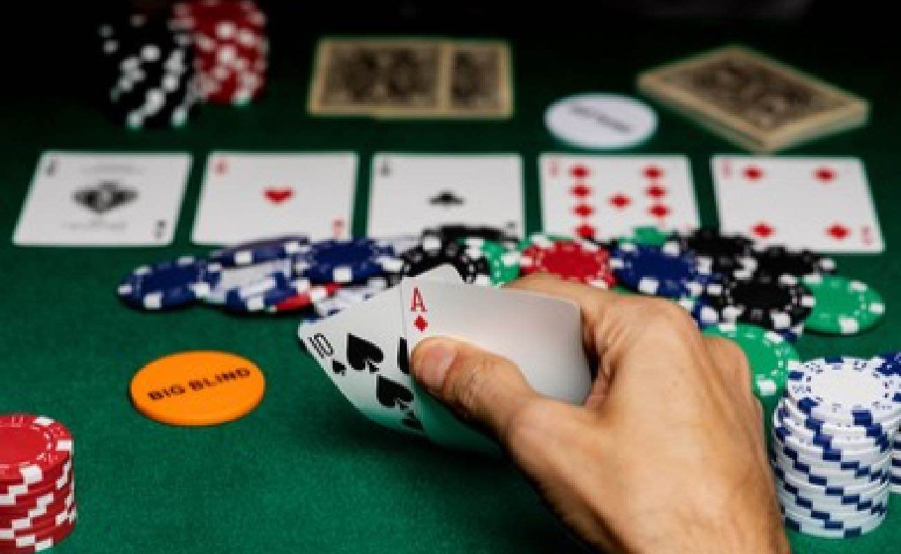 A hand showing an ace in the hole for four aces in Texas Hold-em, on a green felt table with betting 
chips.