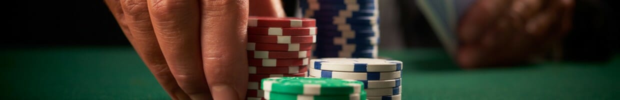 A man picks up some poker chips from the table.