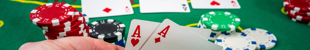 A woman looking at her playing cards on a poker table with casino chips.