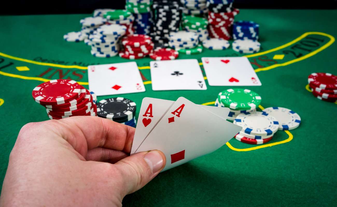 A woman looking at her playing cards on a poker table with casino chips.