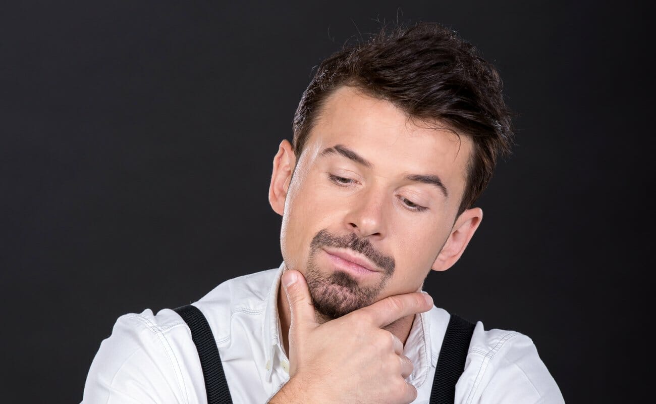 A poker player looks down and strokes his chin while thinking.