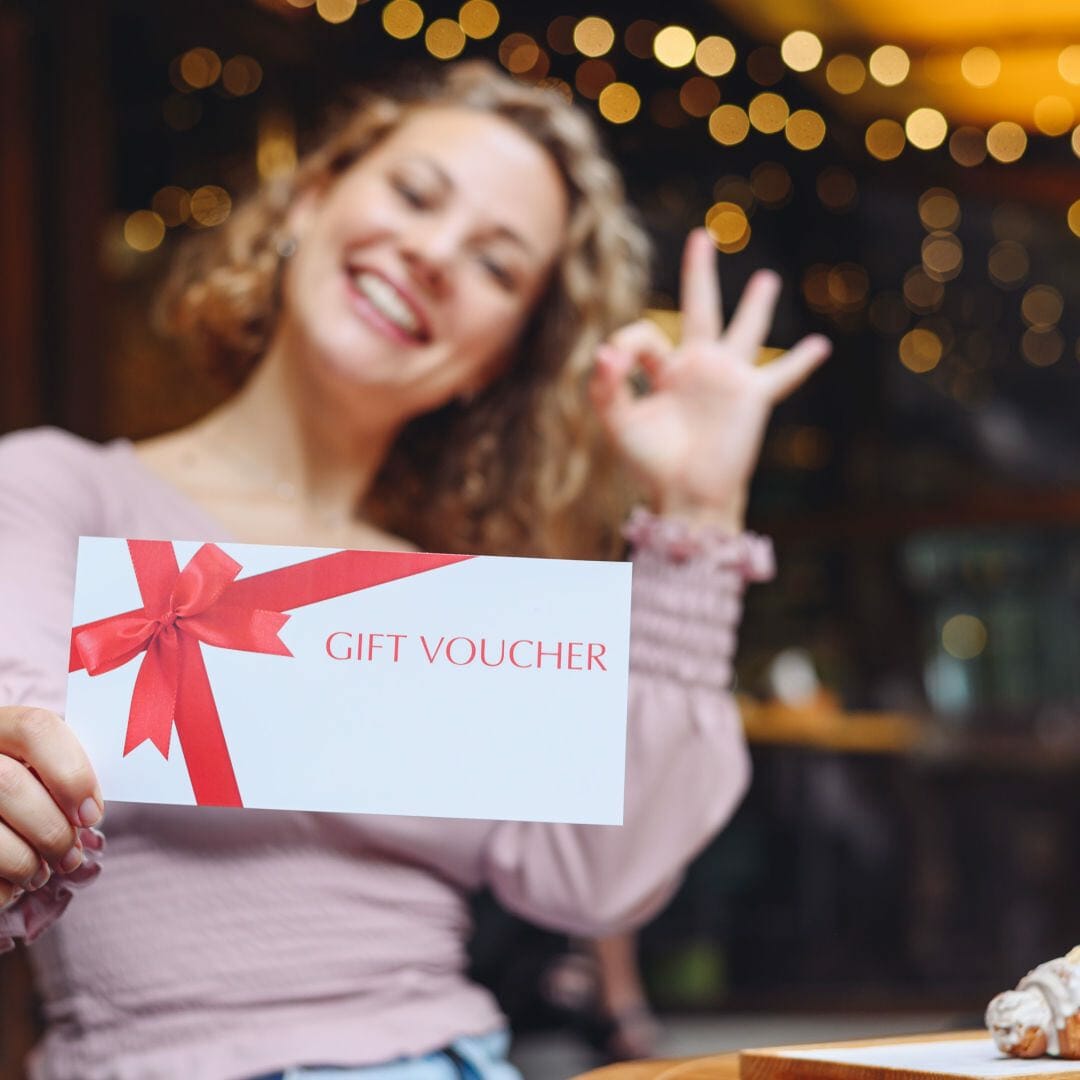 A smiling person holds up a gift voucher.