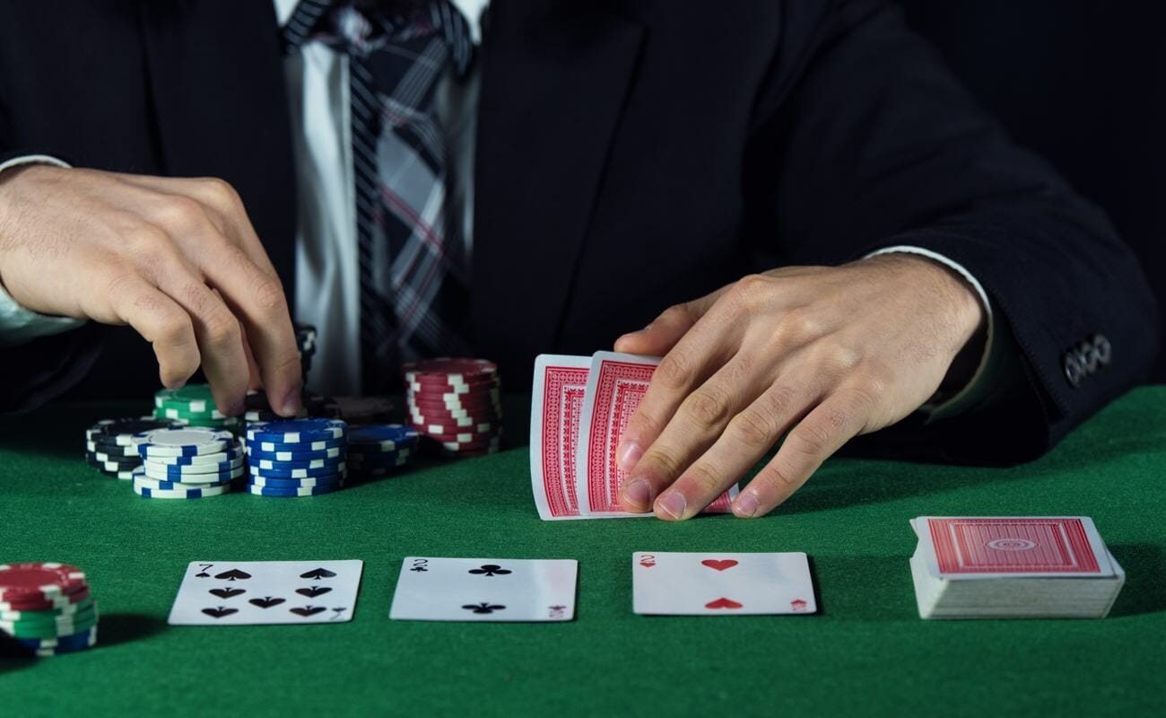 A poker playing looking at his hole cards while counting the chips he wants to bet.