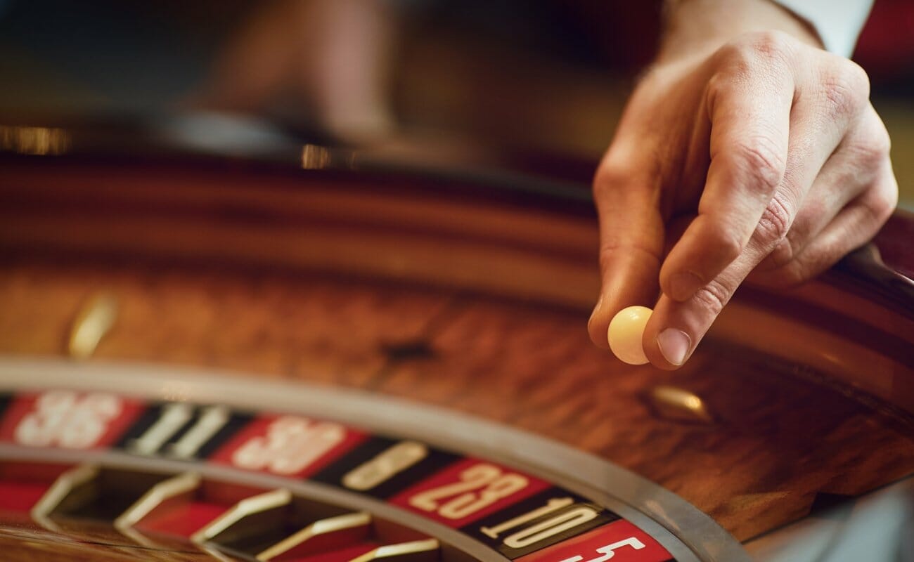A roulette croupier about to drop the ball into the roulette wheel.