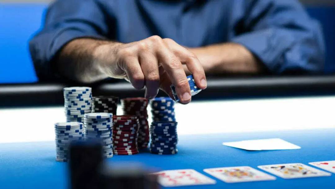 A poker player picking up a small stack of chips from his pile of large poker chips.
