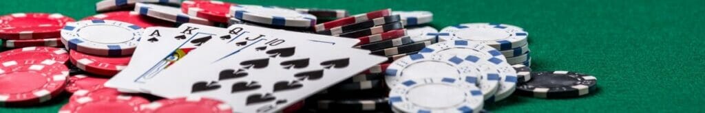 Hero image, close up of a royal flush of spades, five draw card game on a poker table with poker chips