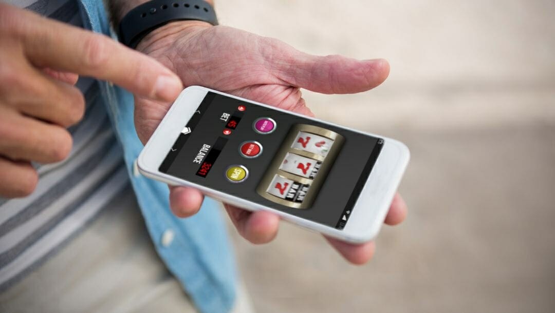 A person holding a cellphone plays online slots. 
