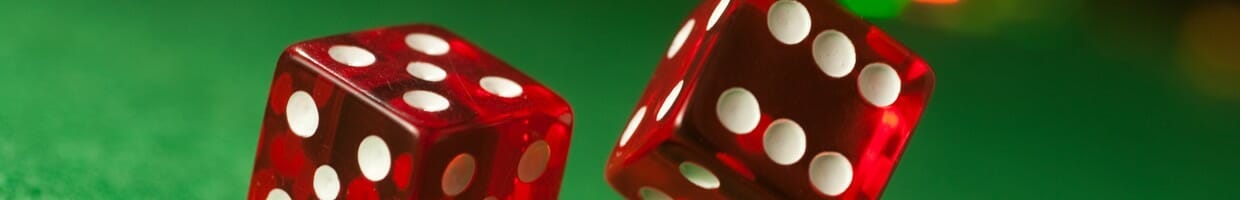 Two dice rolling on a green felt casino table.