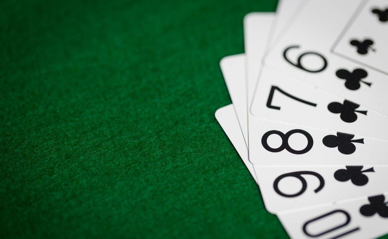 A stack of fanned out playing cards on a green felt table.