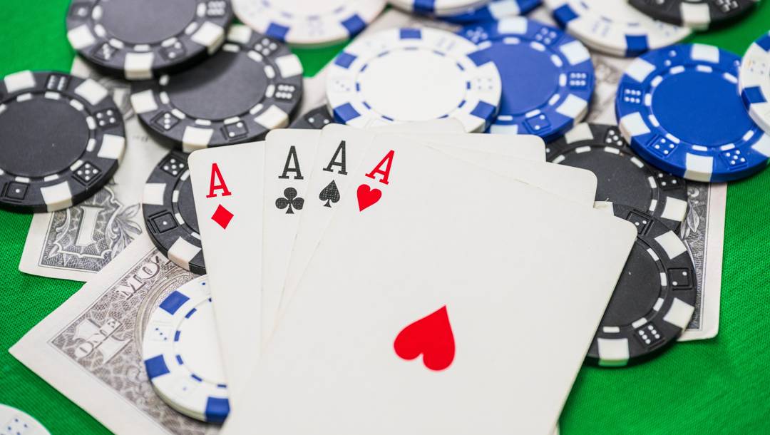 Four aces on scattered poker chips and one dollar bills.