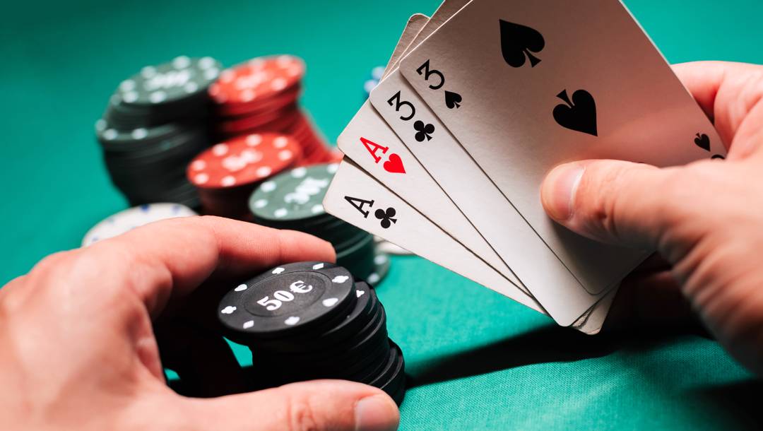 Person holding a pair of aces and threes and a small stack of black poker chips.
