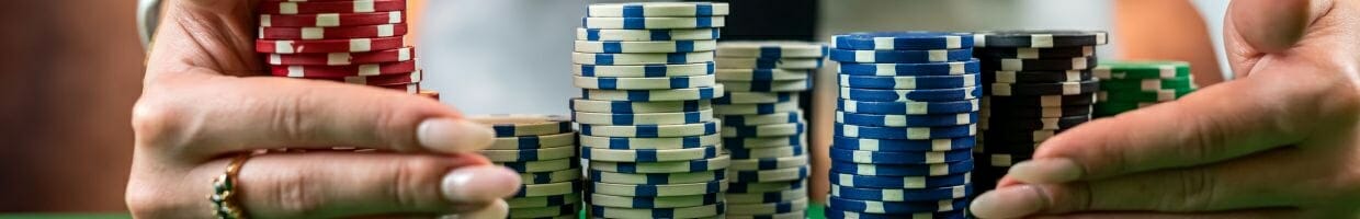 a woman wearing a ring is dragging stacks of poker chips towards herself 