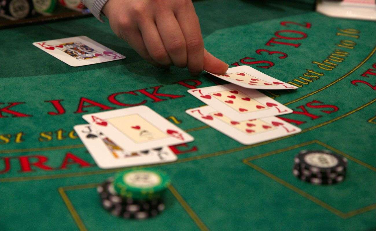 a dealer placing cards down on a blackjack casino table with poker chips on it 