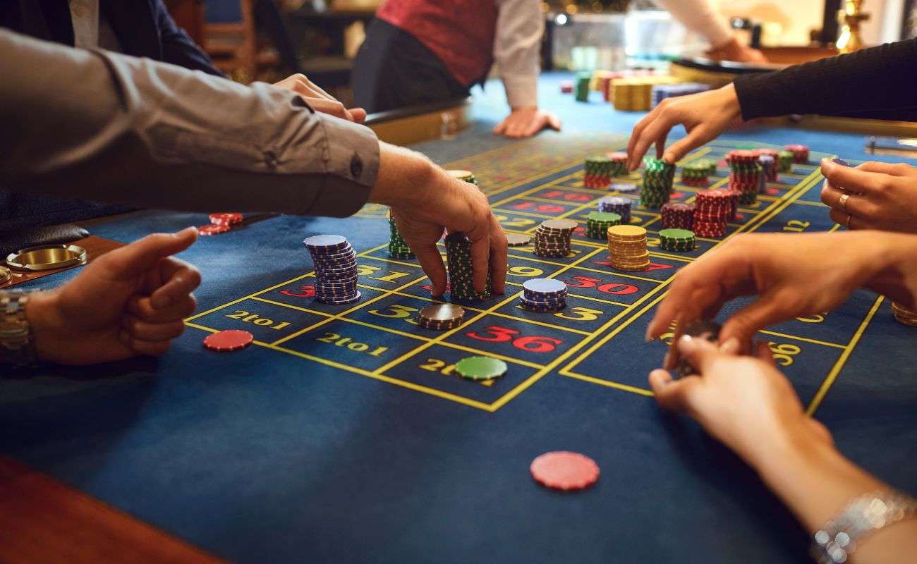 people’s hands placing poker chip bets on a roulette table in a casino
