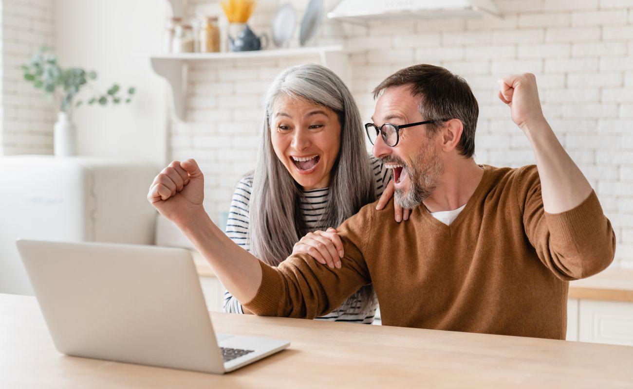 a couple celebrating a win on a laptop 