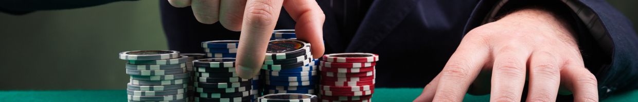 a person picking up a few poker chips off a stack of poker chips on a green felt poker table in a casino