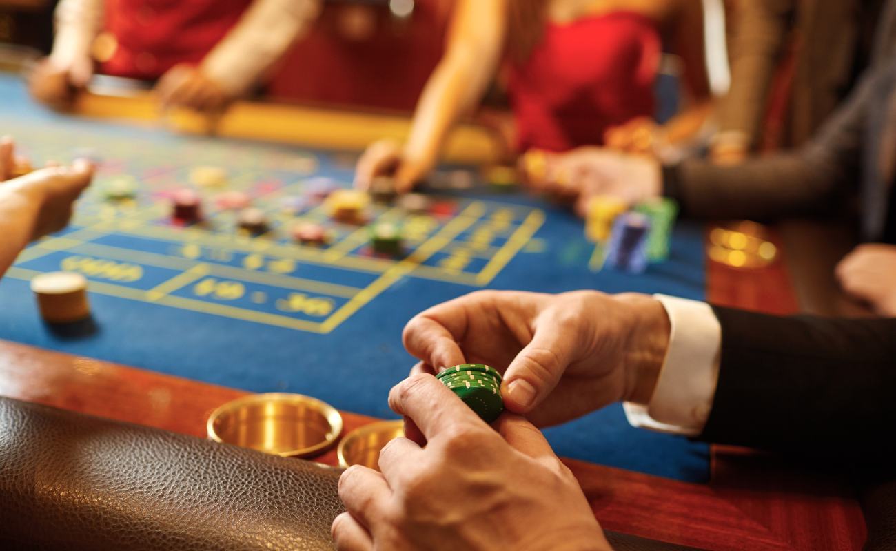 A man holding casino chips between his fingers at a roulette table.