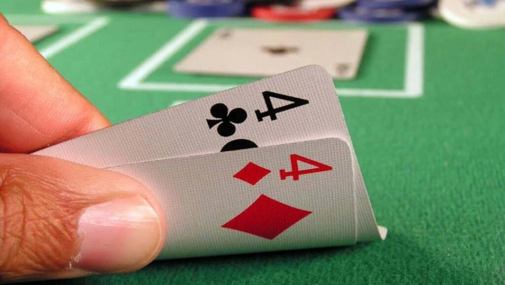 A poker player peeking at a pair of fours.