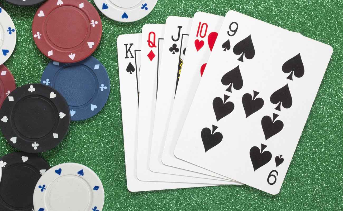 A straight poker hand sitting on a table with poker chips scattered around.