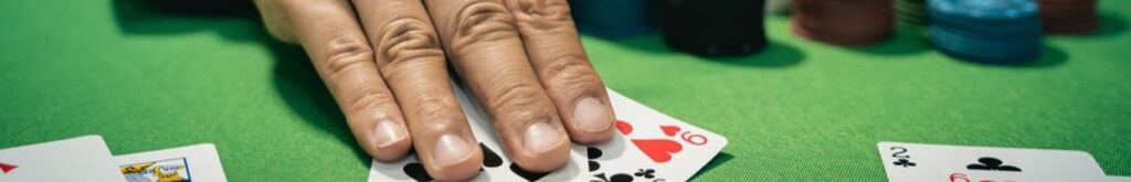 A hand holding poker cards on a green felt table, surrounded by casino chips.