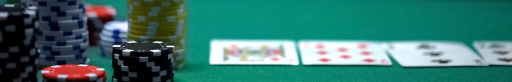Stacks of poker chips and playing cards face up on a green felt poker table