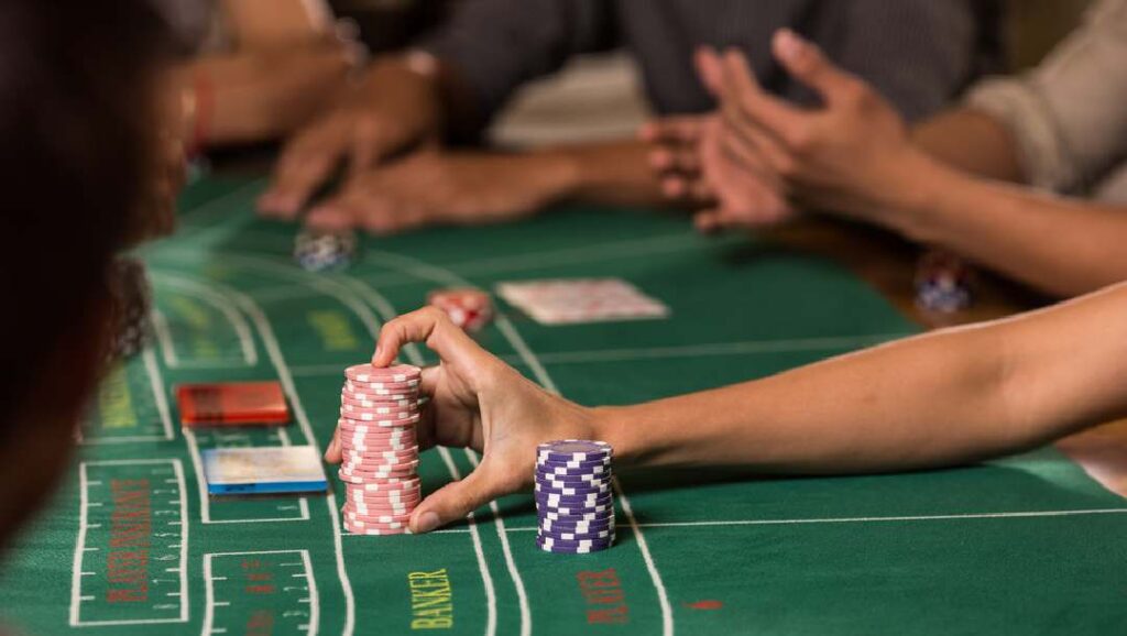 A player pushing chips forward at a baccarat table