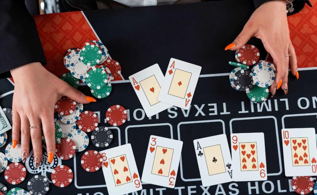 A top-down view of the hands of a female dealer at a No Limit Texas Hold’em poker table with each hand on stacks of poker chips.