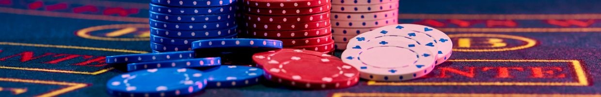 Red, blue, and white poker chips stacked on a poker table. 