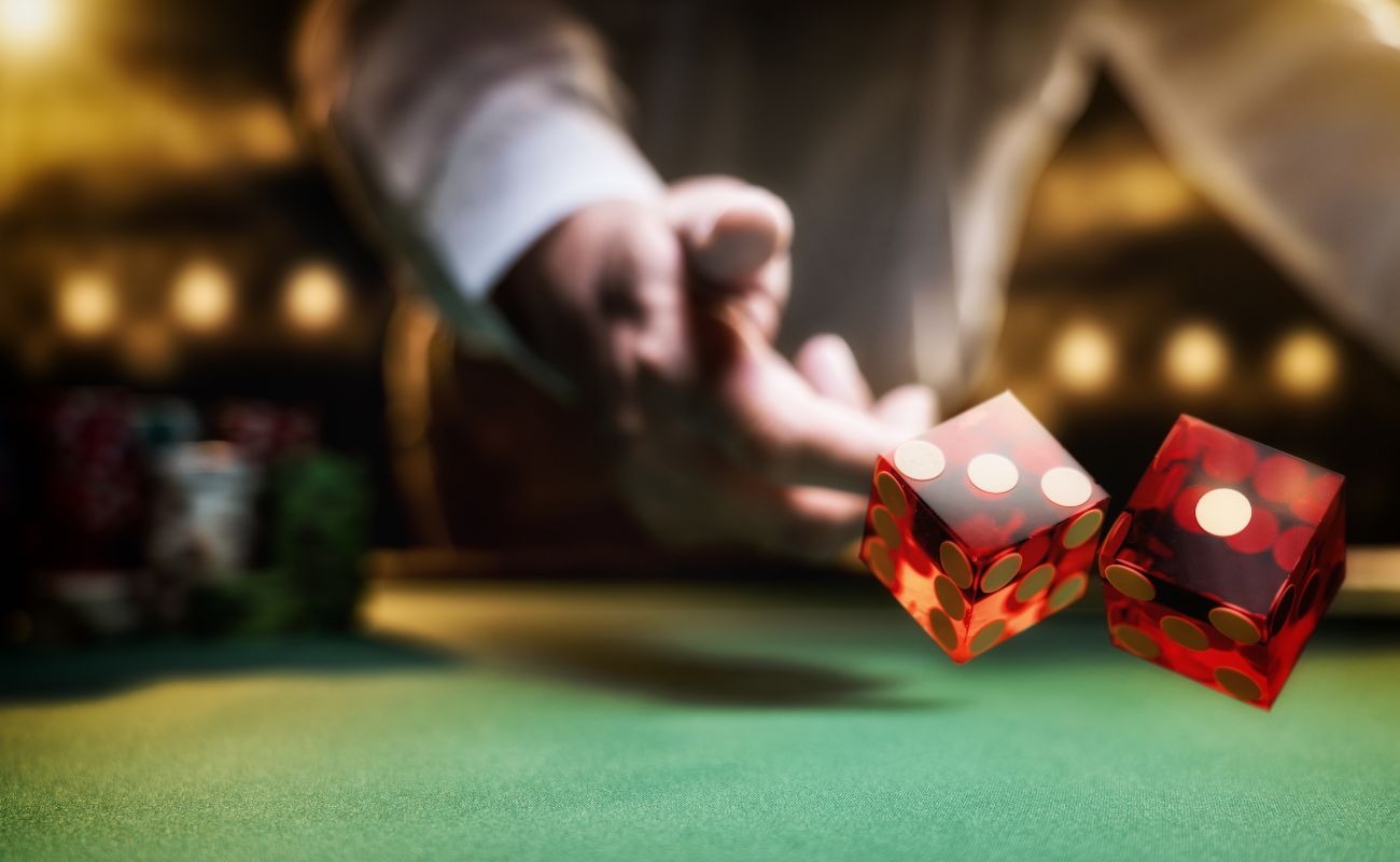 A person throwing two red dice on a craps table. 
