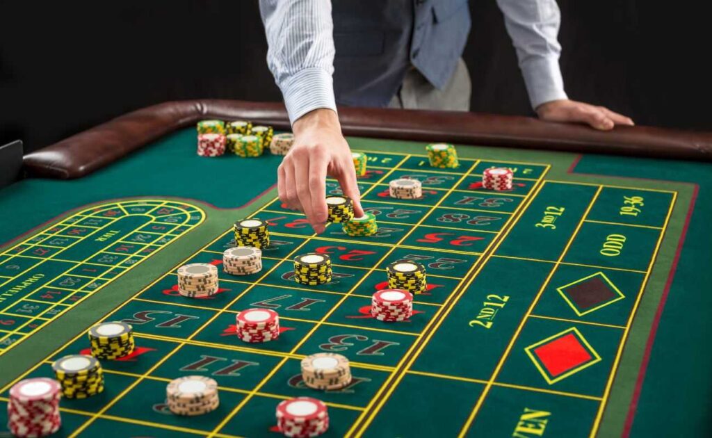 a man placing a stack of poker chips down on a roulette table with other poker chip bets placed on the table 
