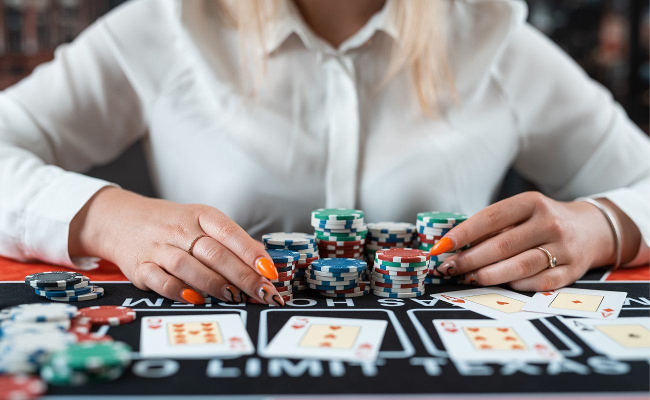 A person sitting at a poker table, with poker chips and playing cards arranged on the table.