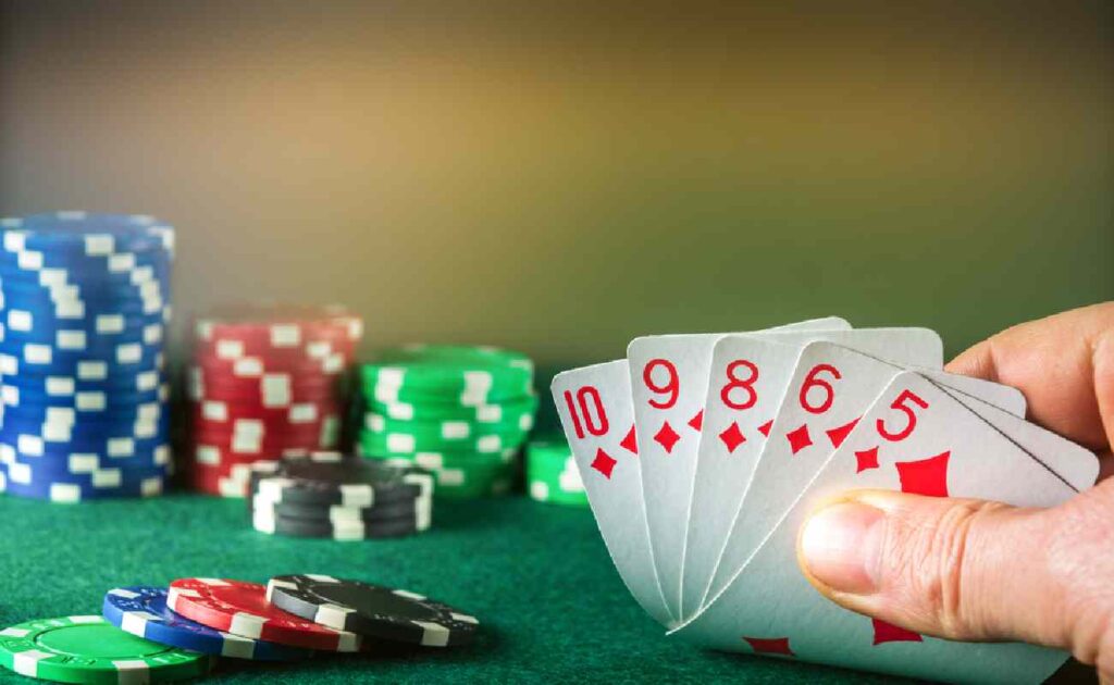 A poker player with a straight flush hand next to some poker chips