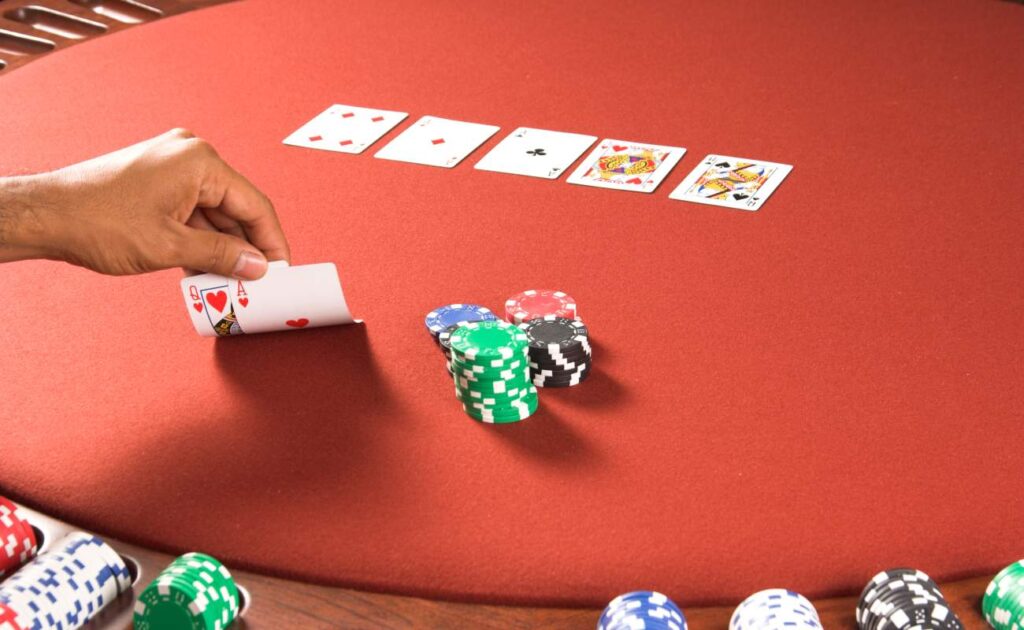 Poker cards and casino chips on a red poker table.