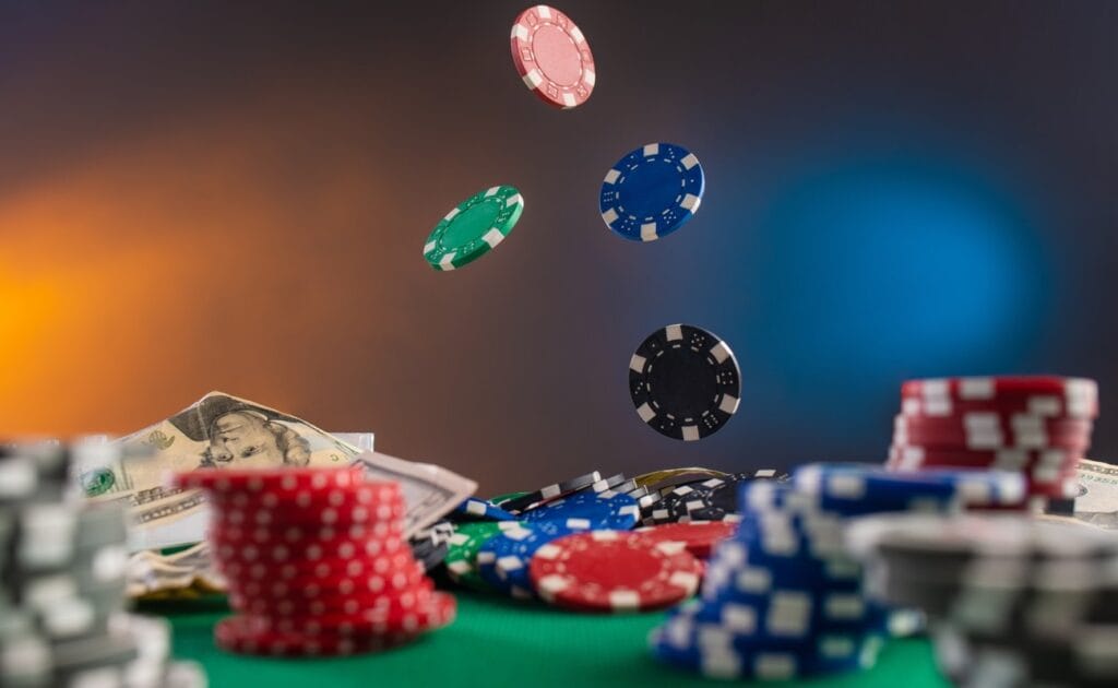 Dollar bills and poker chips sit atop a green felt table