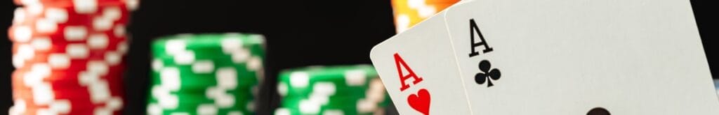 A close-up of a pair of aces with stacks of poker chips in the background.