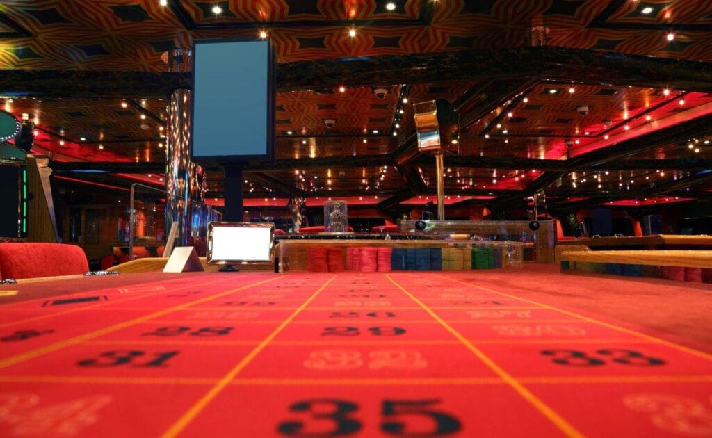 A close-up of a casino table with the rest of the casino clearly visible behind it.