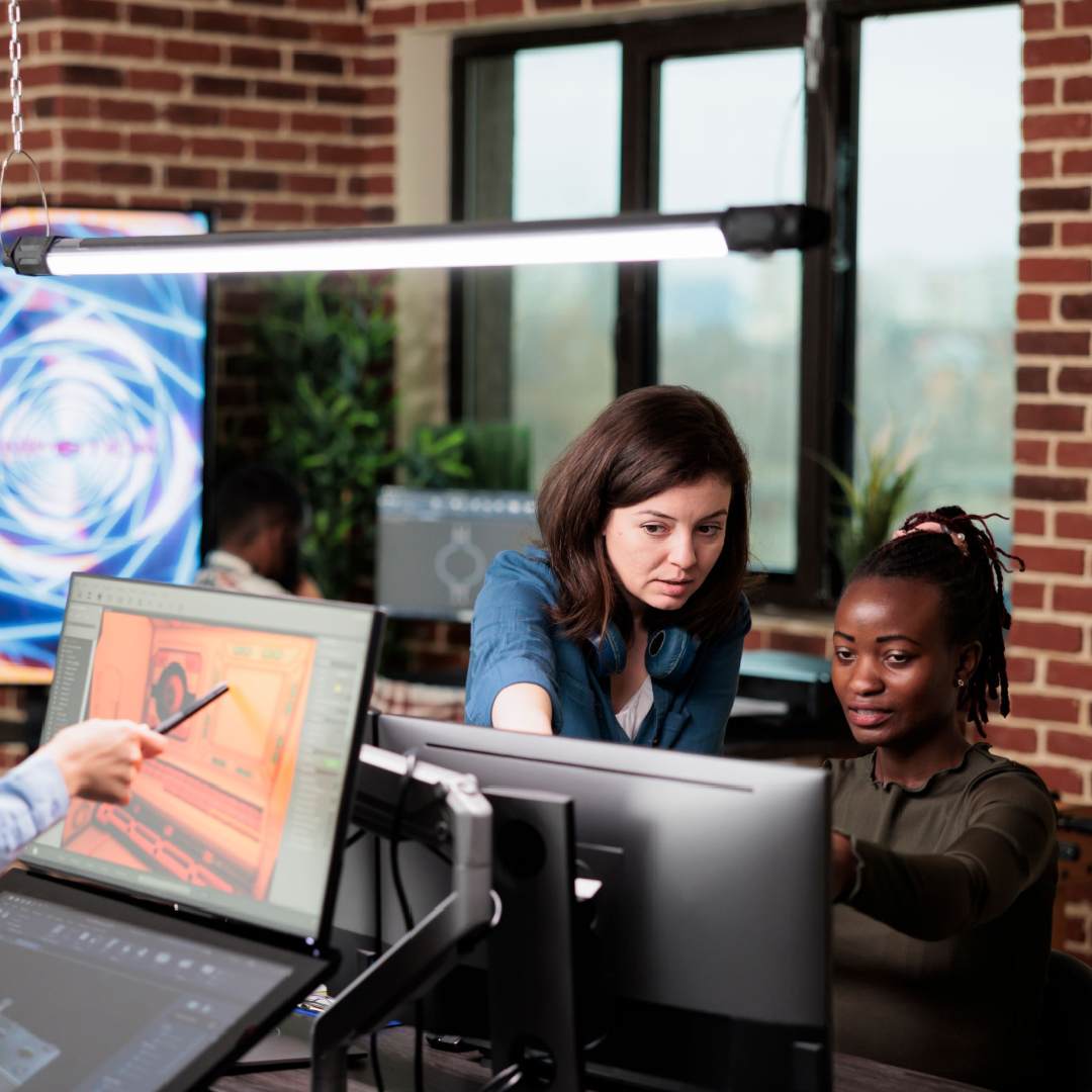 Two people work on a desktop in a studio.